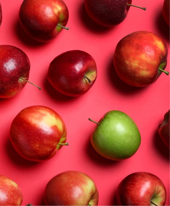 red apples on a red background with one singular green apple